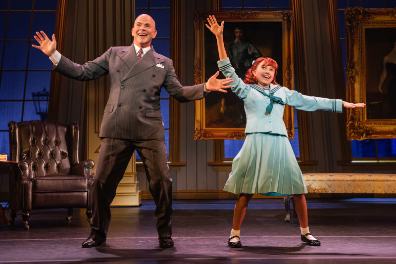 Christopher Swan and Rainier (Rainey) Treviño in the North American Tour of Annie. Daddy Warbucks and Annie stands side by side smiling and doing different variations of jazz hands.